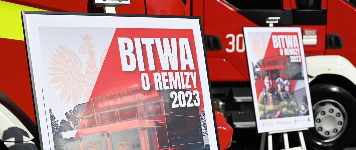 Dwa plakaty promocyjne akcji BITWA O REMIZY 2023 na tle dwóch pojazdów pożarniczych