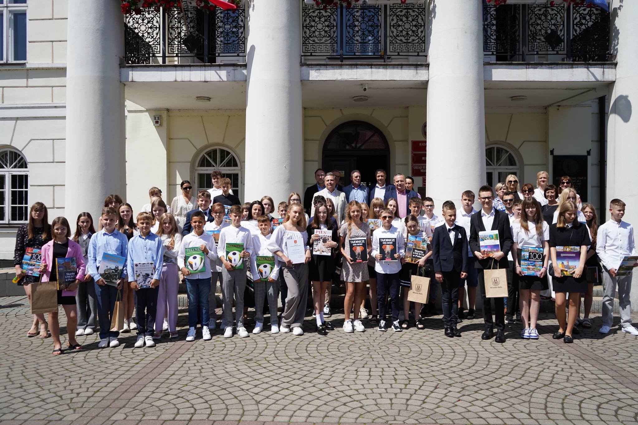 Zdjęcie grupowe nagrodzonych uczniów z Burmistrzem Miasta Koła Krzysztofem Witkowskim przed Ratuszem