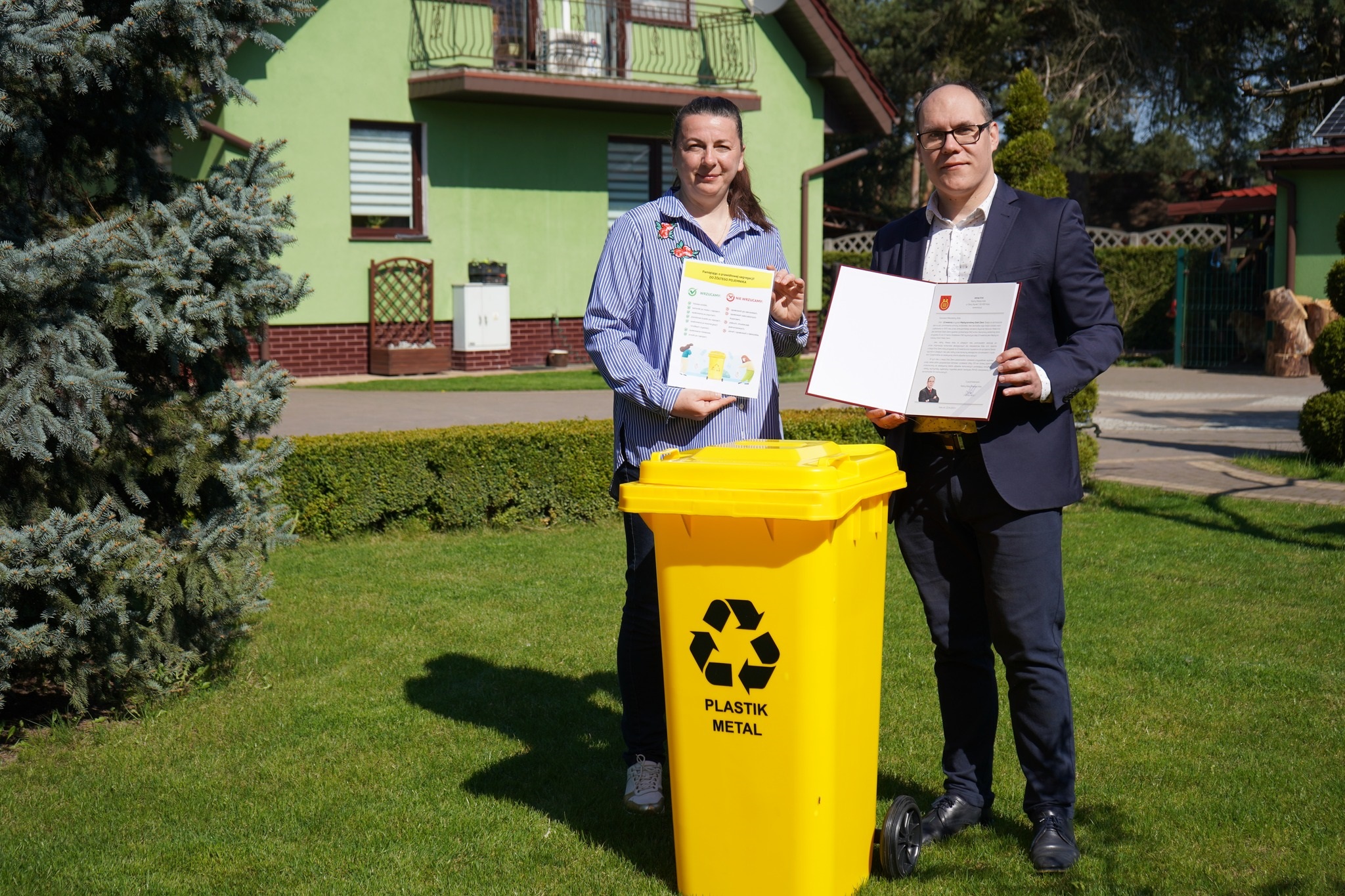 Radny Miejski Adrian Król przekazuje mieszkańce Koła żółty pojemnik do selektywnej zbiórki odpadów