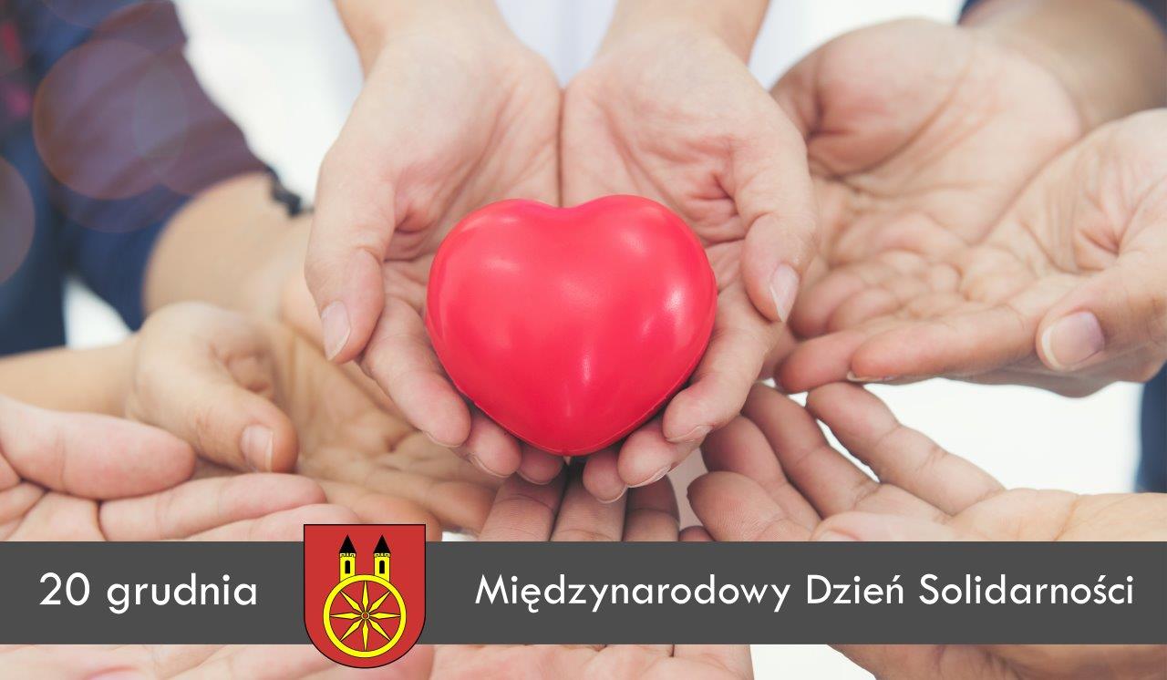 Plansza promująca Międzynarodowy Dzień Solidarności Międzyludzkiej, który obchodzony jest 20 grudnia. Na planszy widać kilkanaście dłoni, w centrum dłonie trzymające czerwone serce. na dole planszy herb miasta Koła.