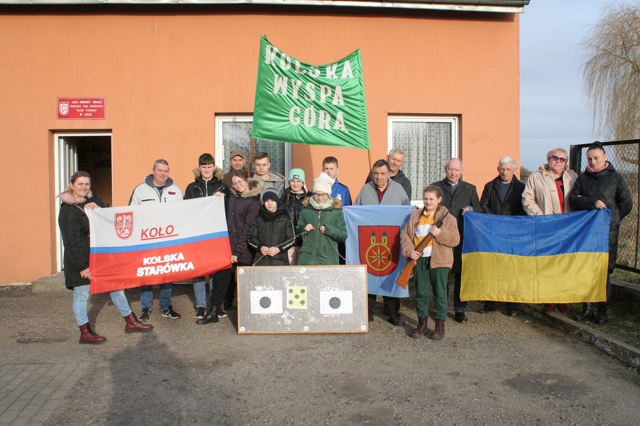 Uczestnicy zawodów strzeleckich w klubie LOK z flagą narodową, klubową LOK i ukraińską