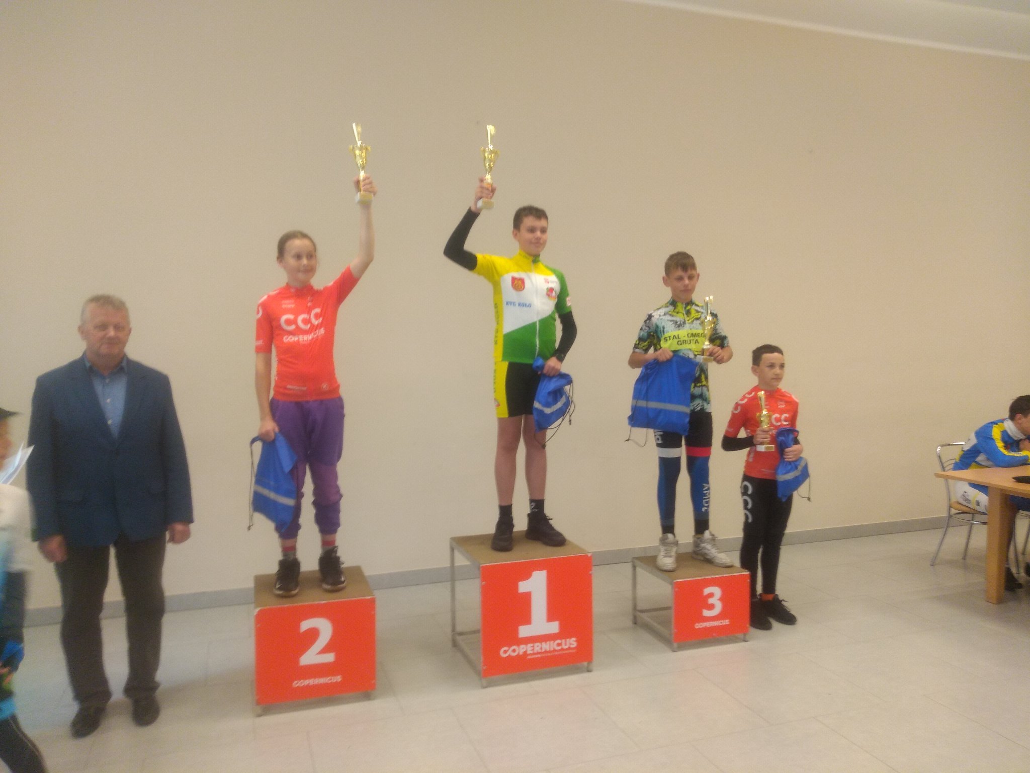 Zawodnik KTC Koło na najwyższym stopniu podium z podniesionym w prawej dłoni pucharem.