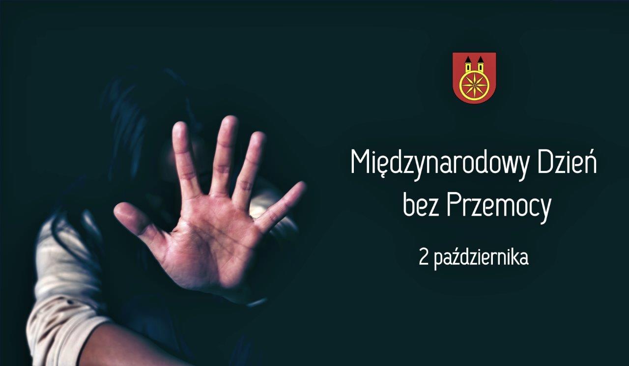 Plansza promująca Międzynarodowy Dzień bez Przemocy. Na czarnym tle widnieje napis: Międzynarodowy Dzień bez Przemocy 2 października. W prawym górnym rogu znajduje się herb miasta Koła, z lewej strony kobieta z wyciągniętą lewą dłonią