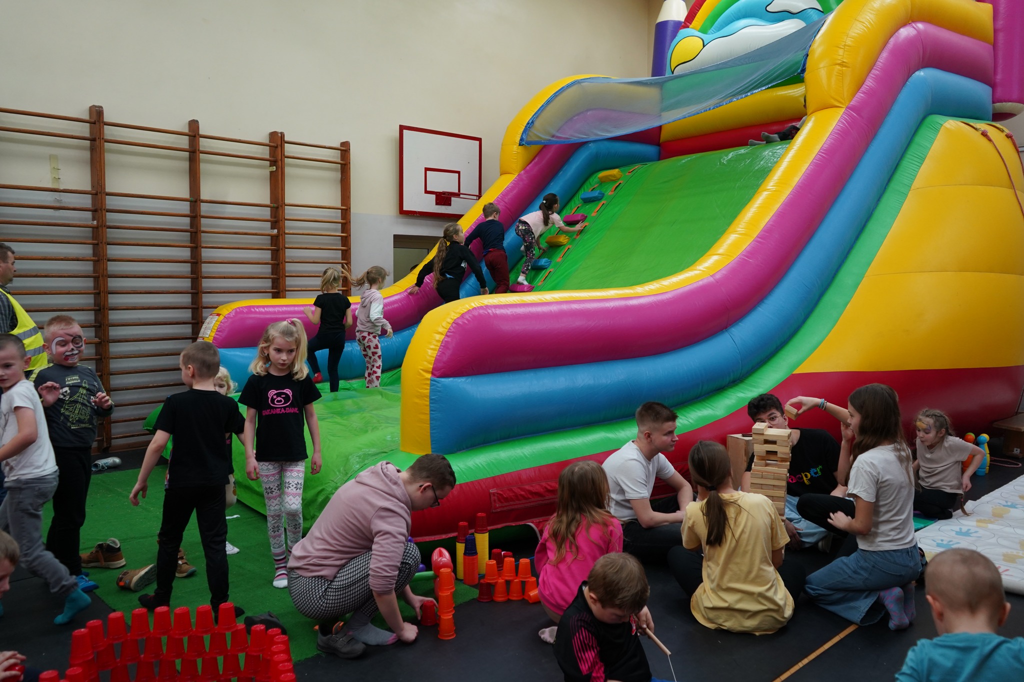 Dzieci bawiące się na dmuchanym zamku w sali gimnastycznej w Szkole Podstawowej nr 3